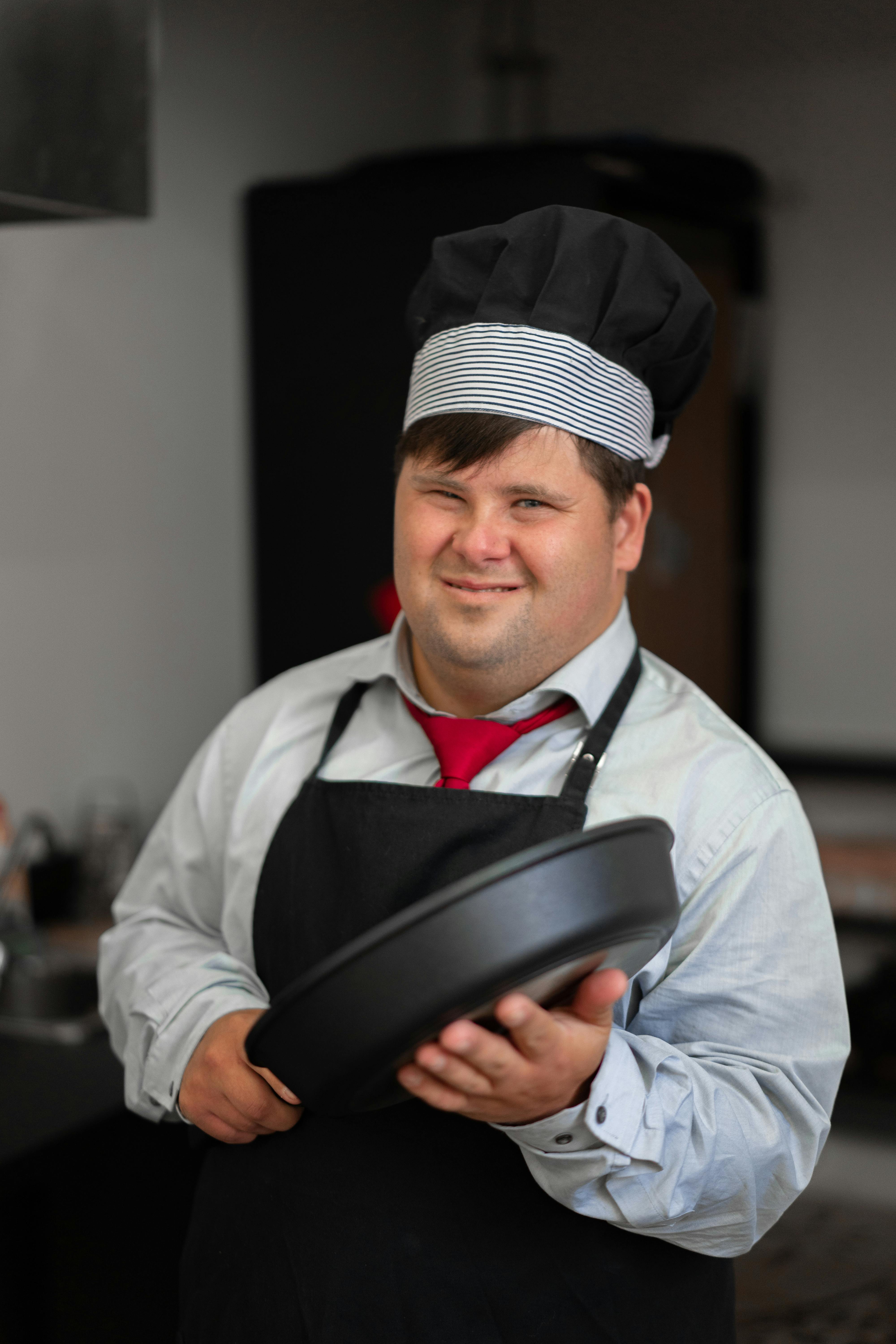 A man in long sleeves and apron holding a pot